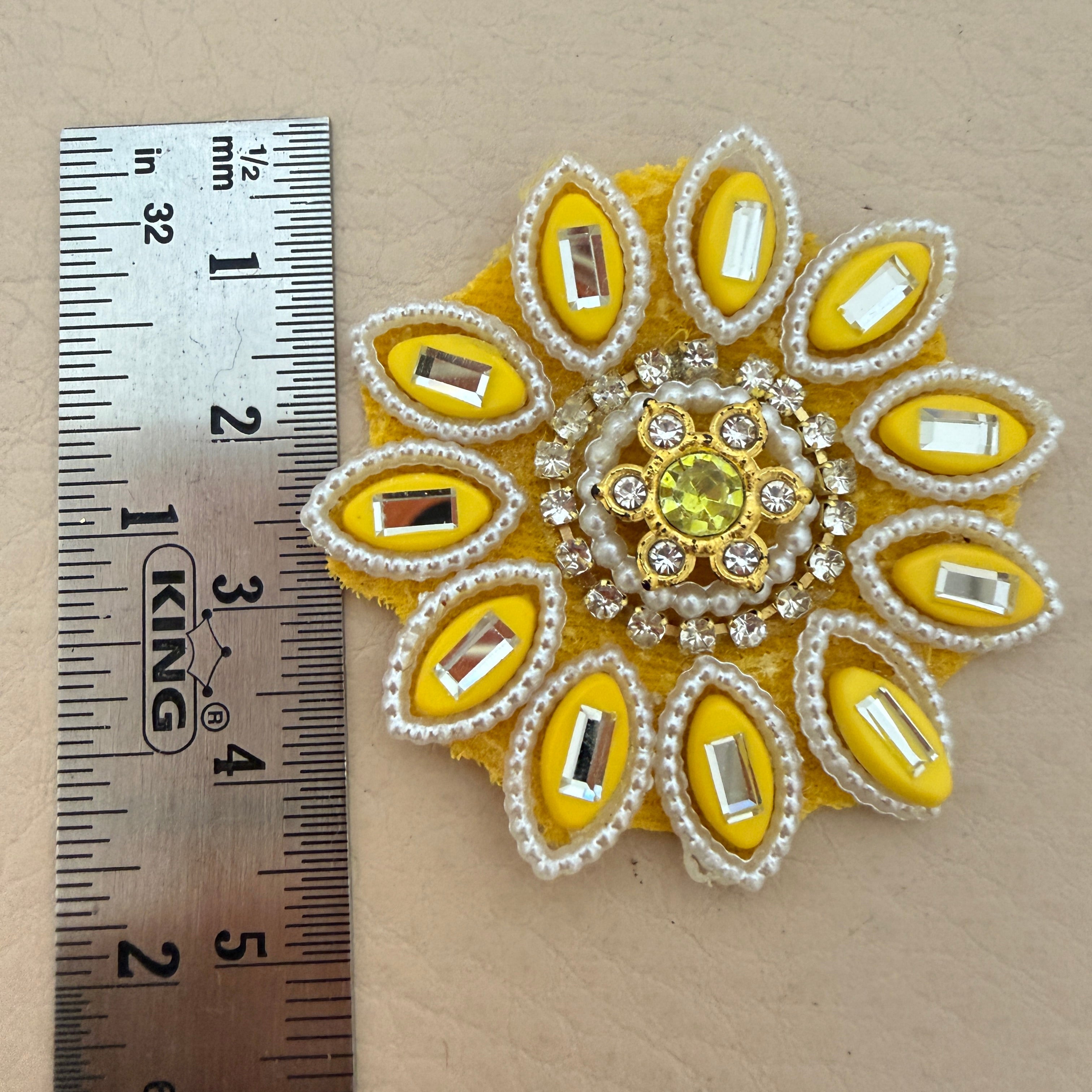Handcrafted yellow floral patch held in hand showing size