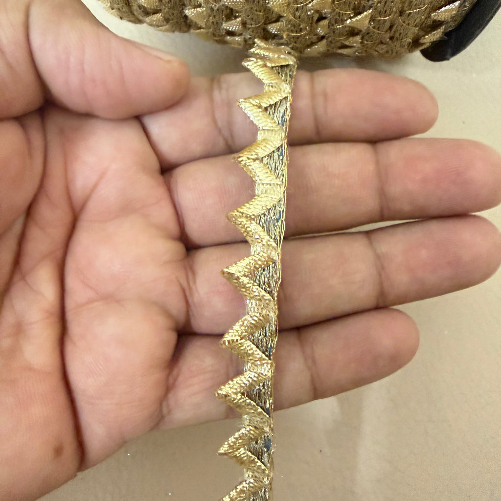 Gold metallic rickrack lace trim on spool with loose length shown